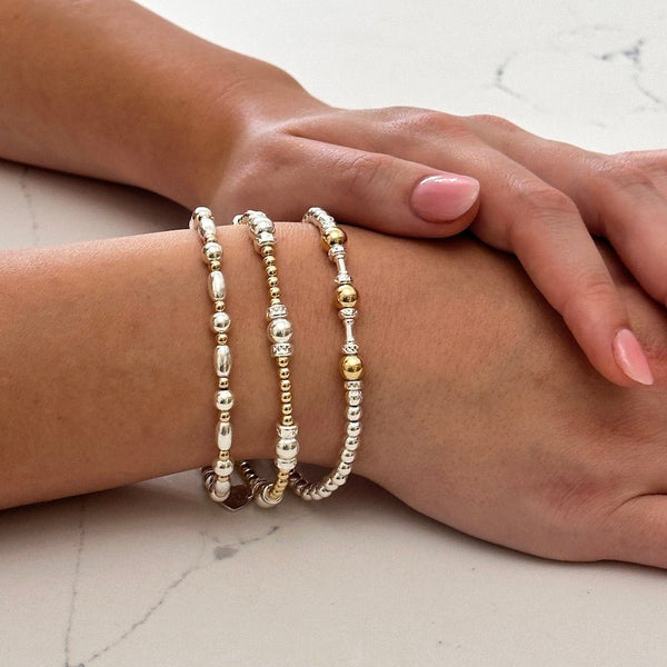 Close up of a woman's wrist wearing three mixed metal sterling silver and gold-filled beaded bracelets