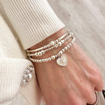 A stack of sterling silver stacking bracelets featuring the Paw Prints on My Heart bracelet