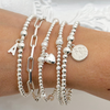 Silver bracelets with various charms on a wrist against a white background