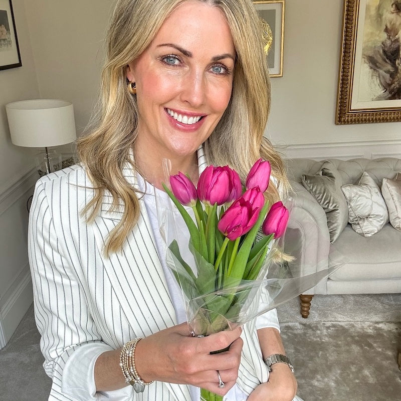 Portrait photo of Becks, aka @thehousebuild, wearing Bella Jane stacking bracelets and holding a bunch of tulips