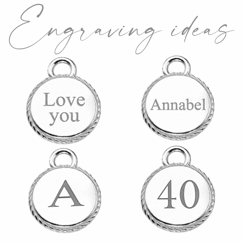Four silver round charm pendants with twisted rope borders on a white background, showing example engravings: 'Love you', 'Annabel', 'A', and '40'. The text 'Engraving ideas' appears in grey script at the top.