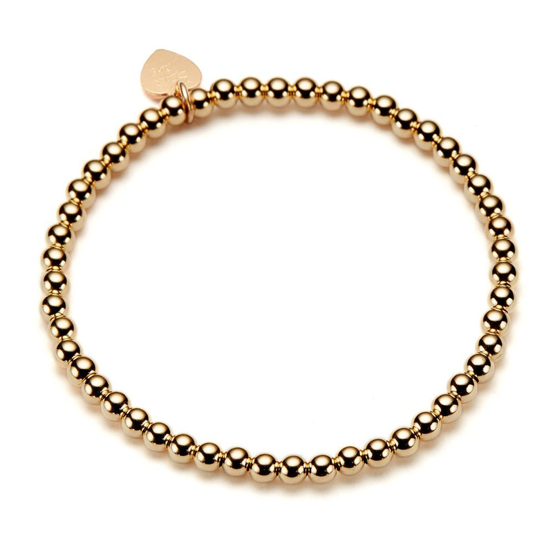 Gold beaded stacking bracelet on a white background