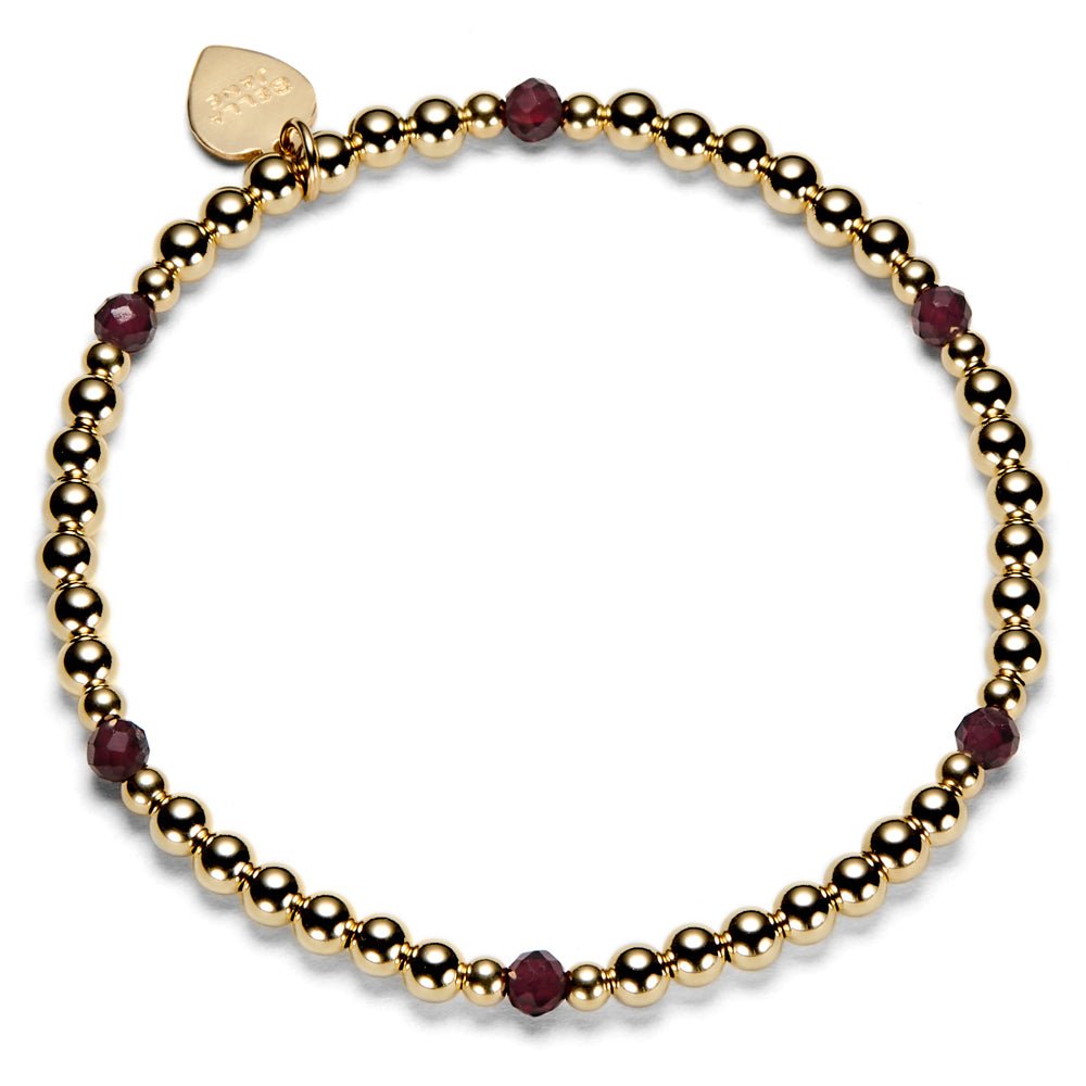 Gold beaded bracelet with red gemstones on a white background