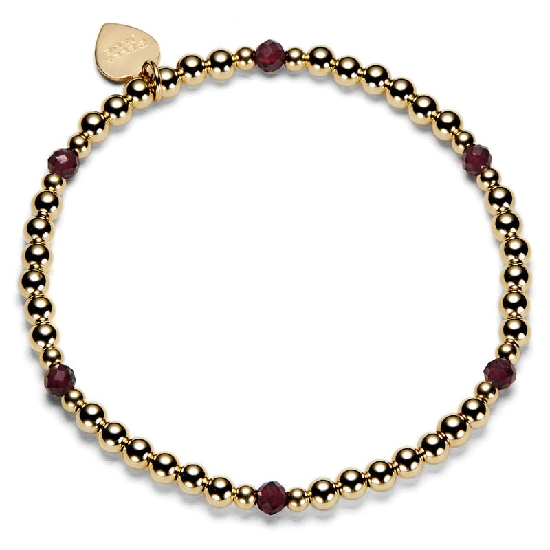 Gold beaded bracelet with red gemstones on a white background