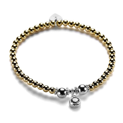 A gold and silver bracelet with a cubic zirconia sparkly charm pictured on a white background.