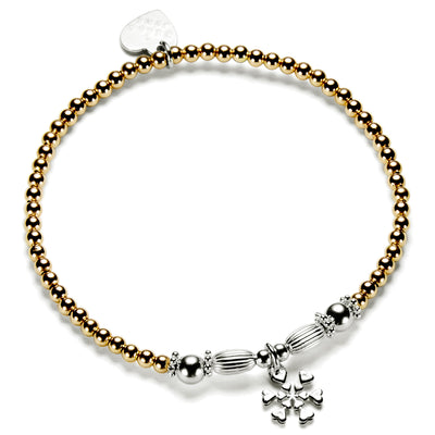 A gold-filled and sterling silver beaded stacking bracelet with oval and round focal beads and a sterling silver snowflake charm.