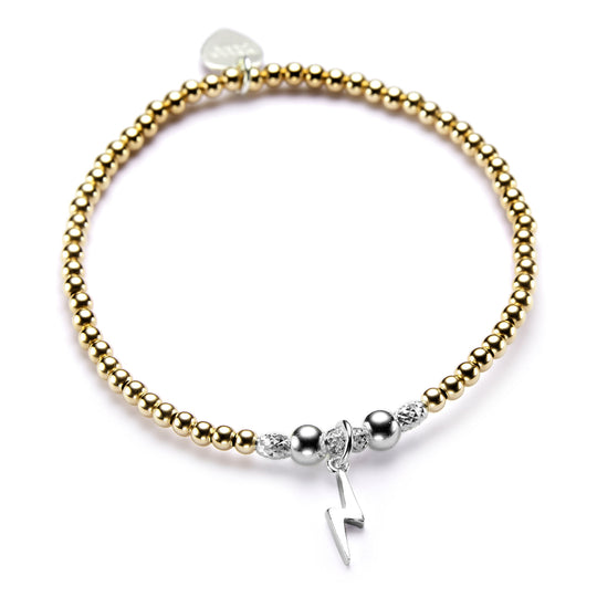 A gold stacking bracelet with a sterling silver lightning charm.