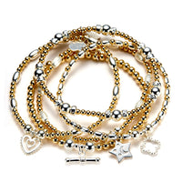 Stack of gold and silver beaded bracelets with charms on a white background
