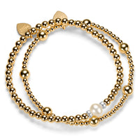 2 gold beaded bracelets, one with a focal pearl, against a white background