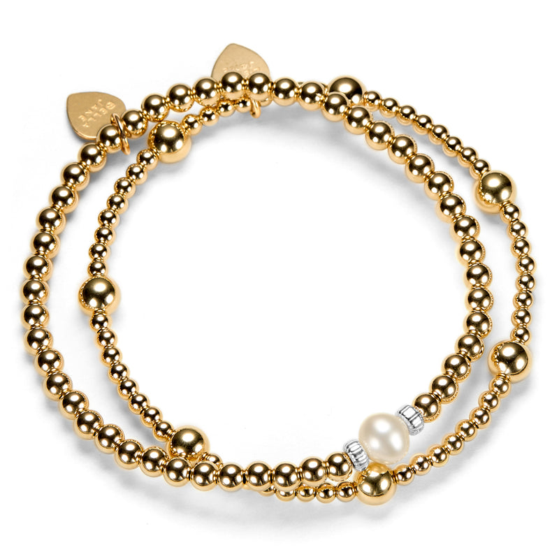 2 gold beaded bracelets, one with a focal pearl, against a white background