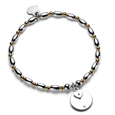 Silver and gold beaded bracelet with round disc and heart-shaped charms on a white background