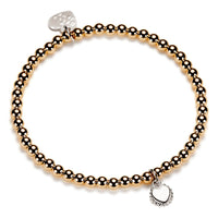 Gold beaded bracelet with heart-shaped disc charm on a white background