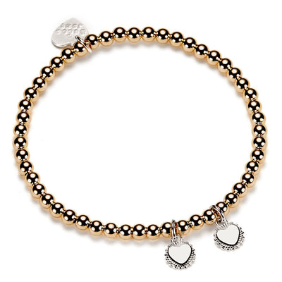 Gold beaded bracelet with heart charms on a white background