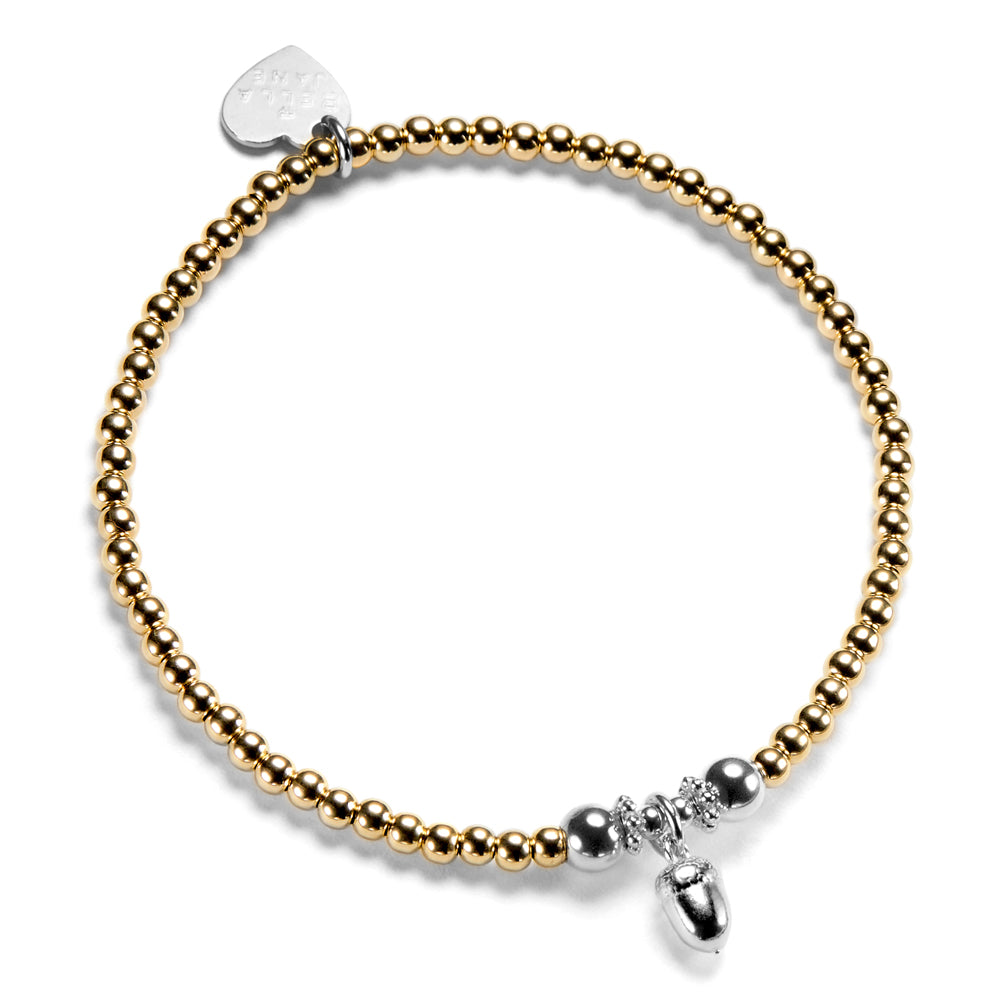 Gold and silver beaded bracelet with a small acorn charm on a white background