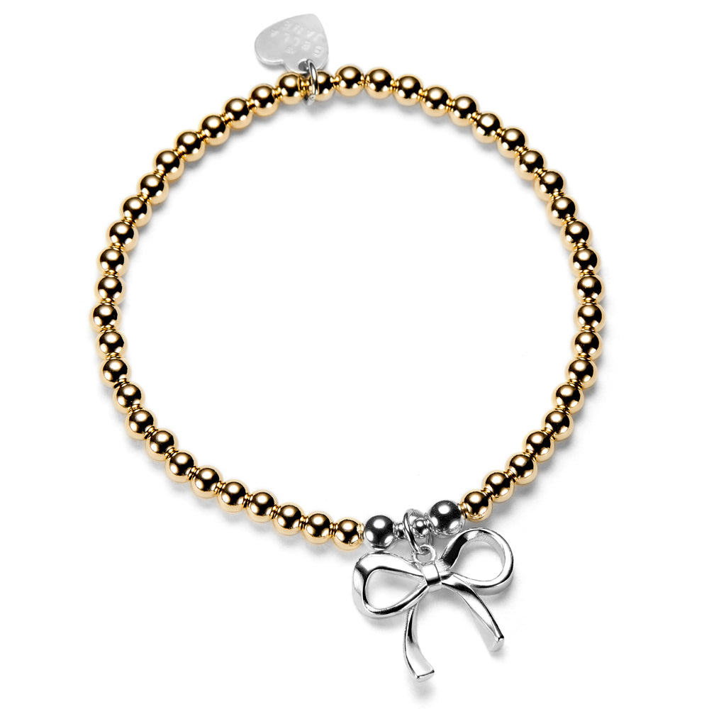 Gold beaded bracelet with a silver bow charm on a white background