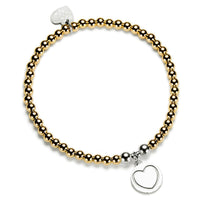 Bracelet with gold and silver beads and  round silver disc charm with a heart on it, on a white background
