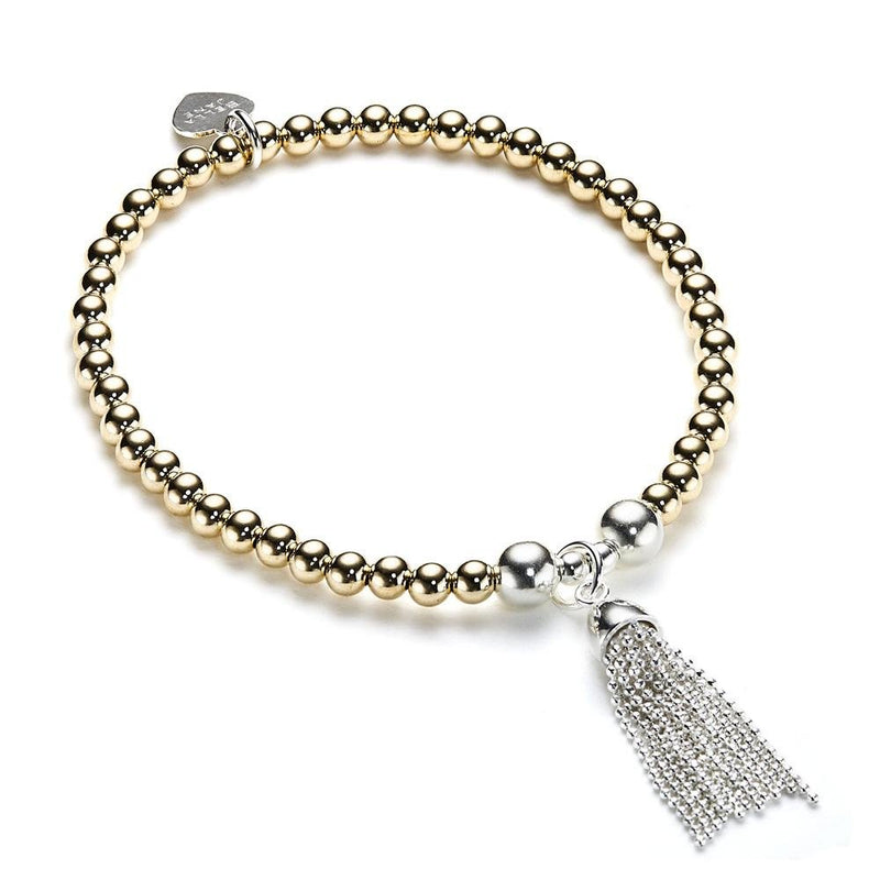 Beaded gold-filled and sterling silver stacking bracelet with silver tassel charm on a white background