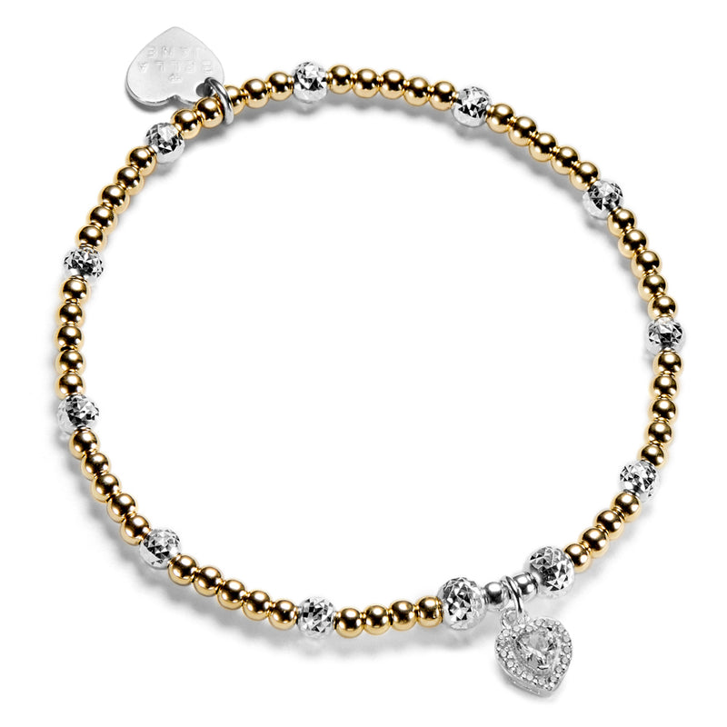 Gold beaded bracelet with a few silver beads and a silver and cubic zirconia heart charm, on a white background