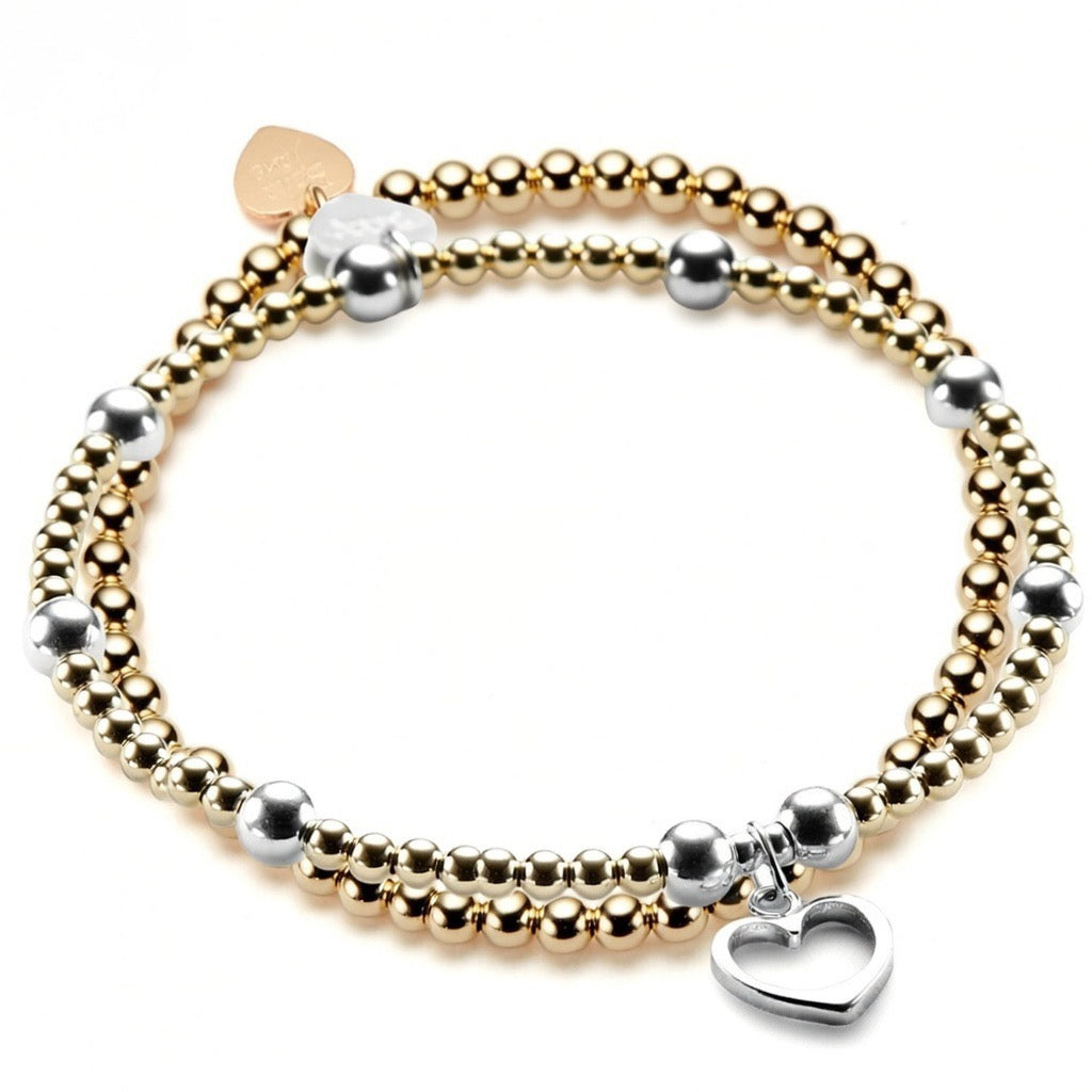 Two gold and silver beaded bracelets with a silver heart charm on one of the bracelets, on a white background