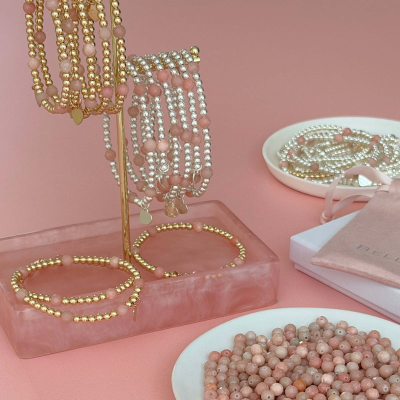 Bella Jane Jewellery display with sterling silver and gold-filled with pink opal stacking bracelets, on a pink surface and a dish of pink opal beads