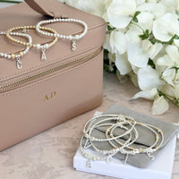 A selection of sterling silver and mixed metal Bella Jane beaded stacking bracelets, featuring sterling silver initial charms, against a floral background.