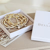 A stack of beaded bracelets resting on a Bella Jane pouch and in a Bella Jane box