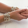 Close-up of a woman's wrists, wearing a stack of sterling silver and gold-filled beaded bracelets on each wrist.