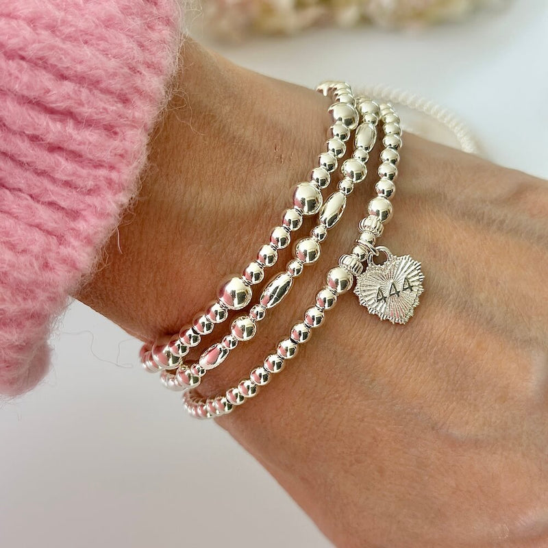 Silver beaded bracelet with heart-shaped charm featuring angel number 444 on the front of the charm, on a white background.