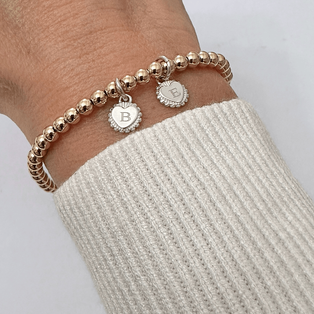 Gold bracelet with silver charms on a wrist against a white background