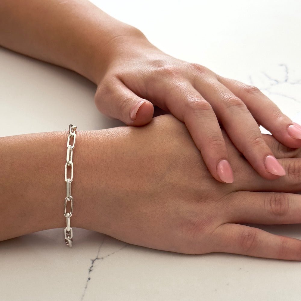 Close up of a wrist wearing the bestselling Bella Jane sterling silver Links chain bracelet against a white marble background