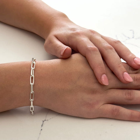 Close up of a wrist wearing the bestselling Bella Jane sterling silver Links chain bracelet against a white marble background