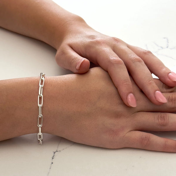 Close up of a wrist wearing the bestselling Bella Jane sterling silver Links chain bracelet against a white marble background