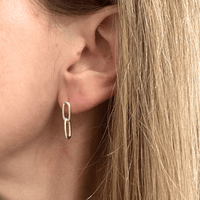 Close-up of a person wearing a silver link chain earring with blonde hair.