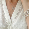 A lady wearing a delicate sterling silver chain with silver bow pendant.