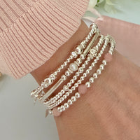 Multiple silver beaded bracelets on a wrist with a light background