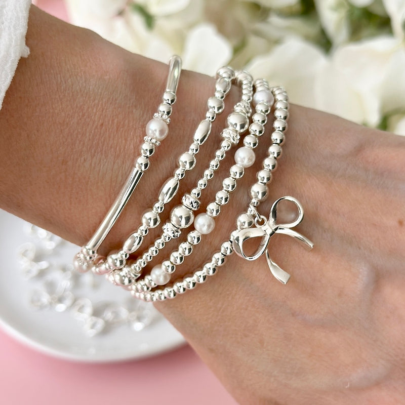 A stack of sterling silver stacking bracelets on a wrist.