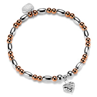 Bracelet with silver and rose gold beads and a silver faceted heart charm on a white background