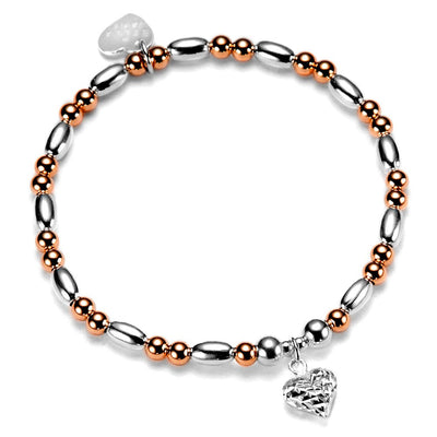 Bracelet with silver and rose gold beads and a silver faceted heart charm on a white background