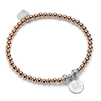 Rose gold beaded bracelet with silver charms on a white background