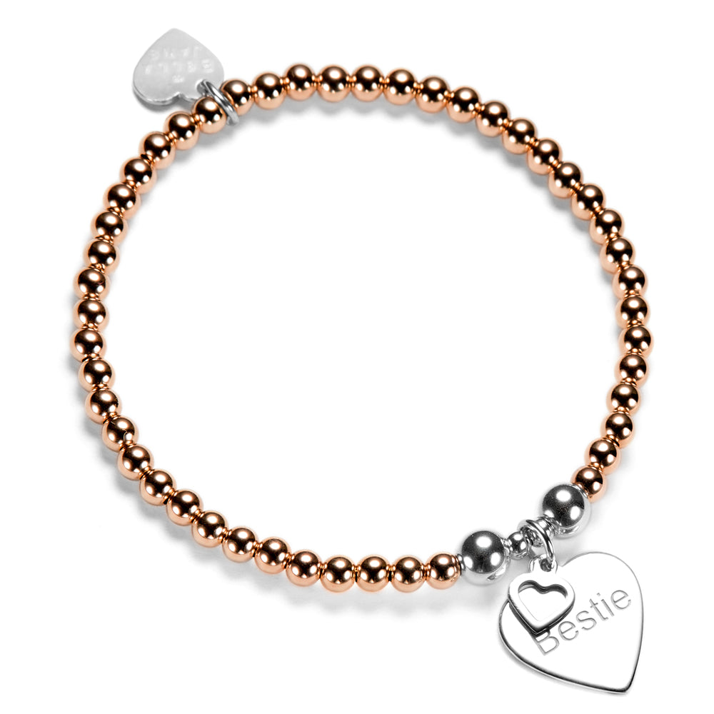 Rose gold-filled and silver mixed-metal beaded bracelet with a silver heart-shaped charm, featuring the word Bestie, on a white background.