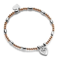 Rose gold ands silver beaded bracelet with silver heart-shaped charm on a white background
