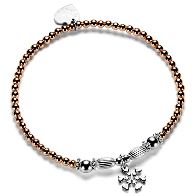 A rose gold and sterling silver beaded stacking bracelet with oval and round focal beads and a sterling silver snowflake charm.