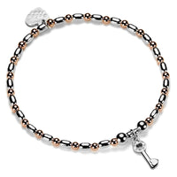 Bracelet with rose gold and silver beads and a silver key charm on a white background