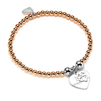 A rose gold beaded bracelet with a silver heart-shaped charm with the words 'Love Luck Happiness' engraved pictured on a white background