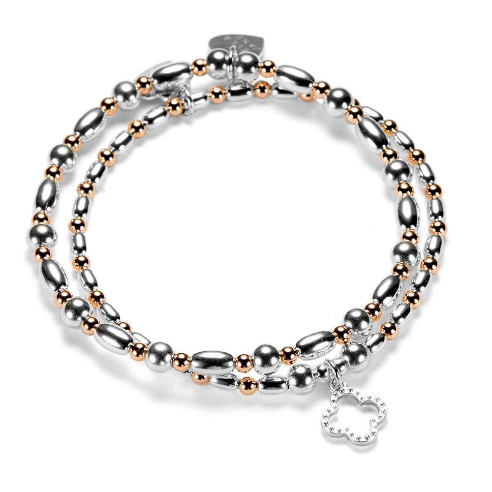 Silver and rose gold mixed-metal beaded bracelet duo featuring an open style, silver studded four leaf clover charm on a white background