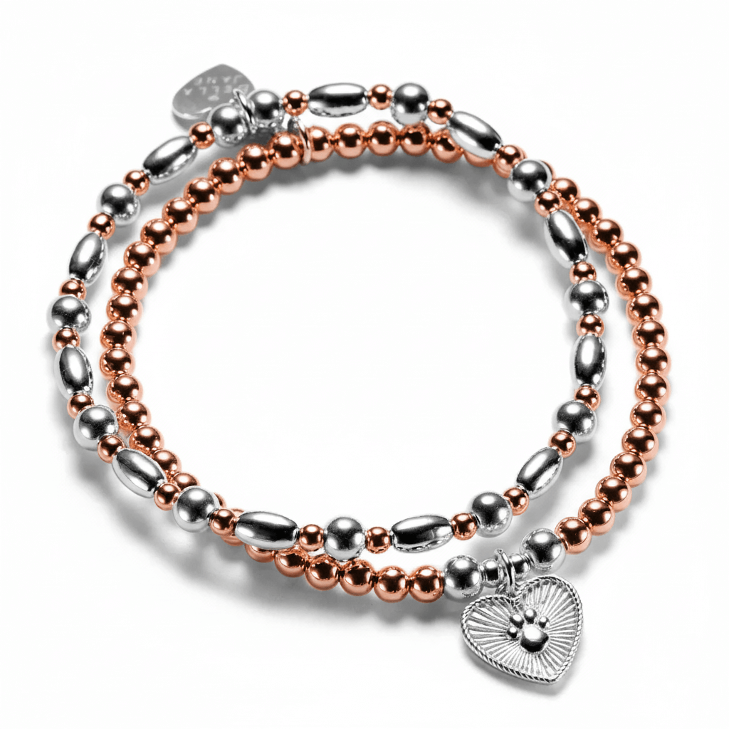 A rose-gold and silver mixed metal beaded stacking bracelet duo with one bracelet featuring a silver paw print heart charm, on a white background