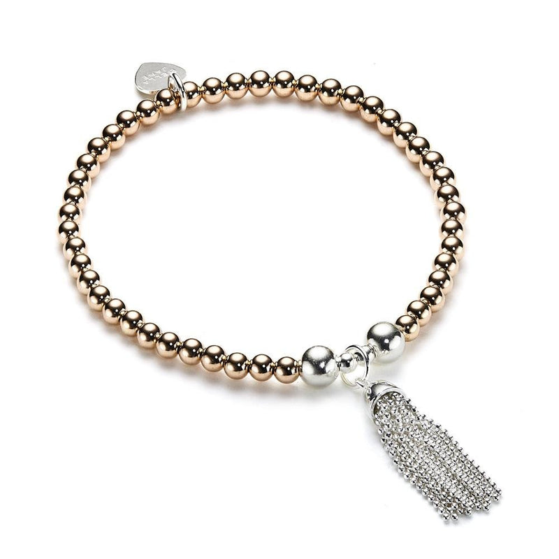 Beaded rose gold-filled and silver stacking bracelet with sterling silver chain tassel charm on a white background