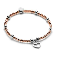 Rose gold and sterling silver beaded bracelet featuring a silver open heart charm on a white background