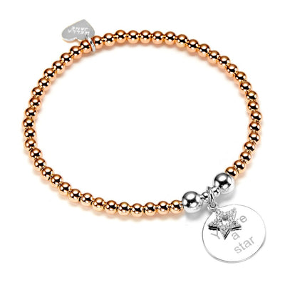 Rose gold beaded bracelet with a silver charm on a white background