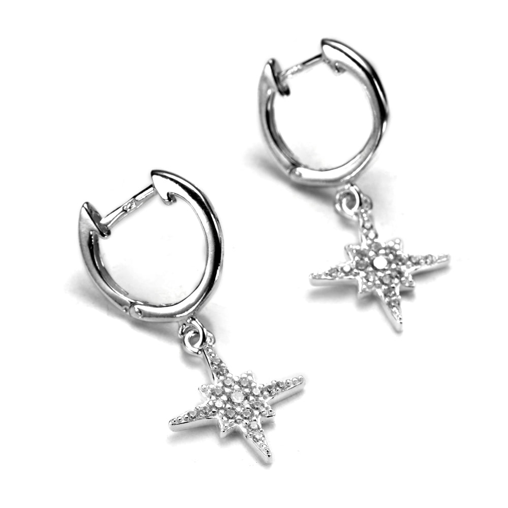 A pair of sterling silver huggie earrings with cubic zirconia starburst charms dangling from them.